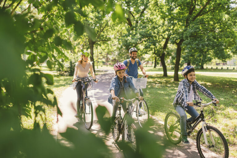 Une maman, un papa et leurs deux enfants roulant à vélo en forêt par un temps ensoleillé